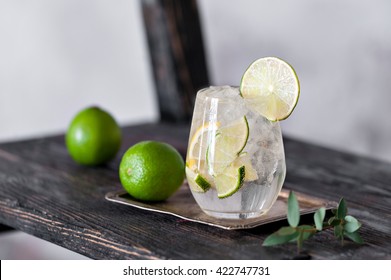 Cold cocktail with lime, lemon, tonic, vodka and ice on vintage background