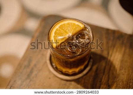 Cold Coffee with Ice Cubes and Orange Garnish in Cozy Cafe Setting