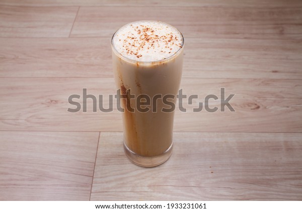 Cold coffee\
milkshake smoothie drink in a glass with coffee beans on a rustic\
wooden table with copy\
space.