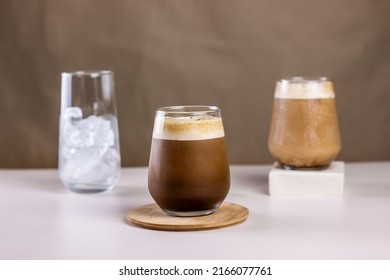 Cold coffee summer drink concept. Different size transparent glasses with ice cube and iced coffee on pastel brown background. - Powered by Shutterstock