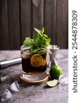 Cold Cuba Libre or Long island iced tea cocktail with brown rum, cola, mint, lime, muddler, jigger and glass