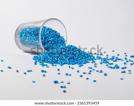 Cold cut pearl blue masterbatch granules spilled from a shot and isolated on a white background, this material is a coloring agent for products in the plastics industry