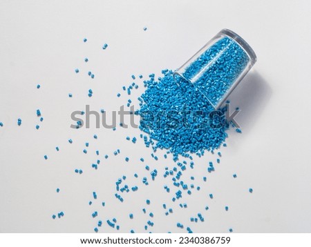 cold cut type blue pearlish masterbatch granules with glass cup in white background photo. This material is a coloring agent for products of the plastics industry