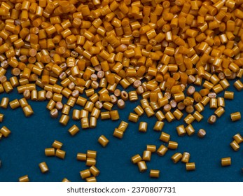 Cold cut type masterbatch granules are orange in color, isolated on a black background. This material is a colorant for products in the plastics industry