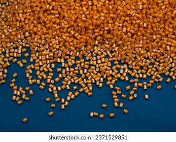 Cold cut type masterbatch granules are orange in color, isolated on a black background. This material is a colorant for products in the plastics industry
