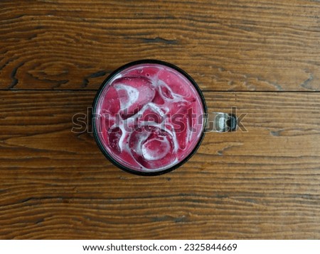 A cold drink called red velvet with a wooden table background. The photo is taken from an aerial view with a landscape style.

