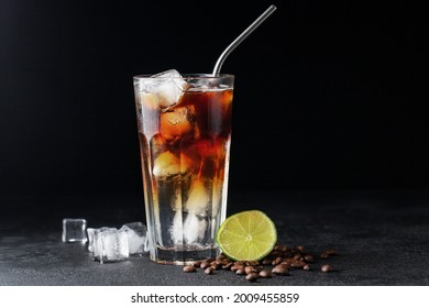 Cold drink with espresso and tonic in glass on black background