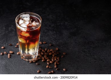 Cold drink with espresso and tonic in glass on black background