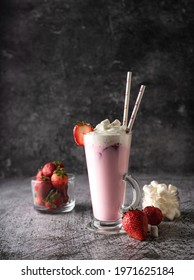 a cold drink. milk strawberry milkshake, with fresh strawberries and cream. in a high transparent glass, a low key, dark moor. copy space