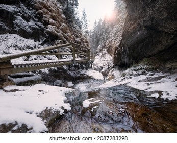 Cold Early Winter Mountain Forest Landscape In Slovakia Tatry Mountain. Small Creek Flowing Down And Washing The Huge Boulders On Its Way. First Sun Rays Lite Young Snow Islands.