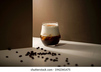 cold espresso coffee with cold milk foam with coffee with brown background  and sprinkled coffee beans on white table - Powered by Shutterstock