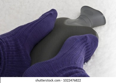 Cold Feet With Purple Socks On A Grey Hot Water Bottle