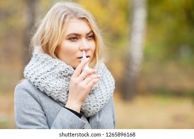 Cold And Flu. Young Sick Woman Uses A Nose Spray At Street Outside.