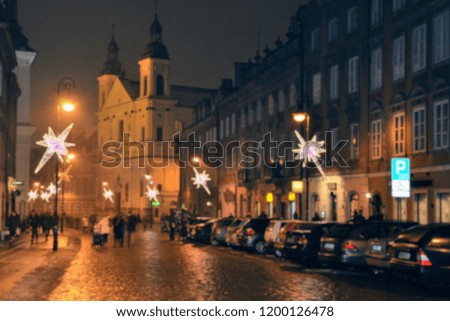 A cold, foggy, rainy December evening in the Warsaw Old Town, Poland. Christmas decorations on the street. Blurred image, out of focus