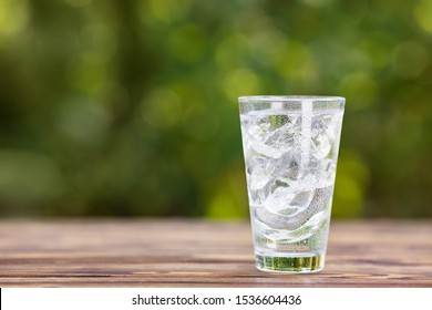 Cold Glass Of Water With Ice On Wooden Table Outdoors