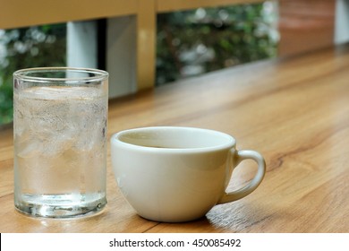 Cold and Hot, a glass of cold water and ice with a cup of coffee with stain on mouth of cup, placing on wooden table. Selective focus on a cup and a glass. - Powered by Shutterstock