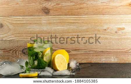 Cold iced mojito, lemon water drink, mint lemonade or lemon cocktail on wood rustic background with copy space for text