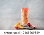 Cold iced peach raspberry bubble tea with juice balls in glass