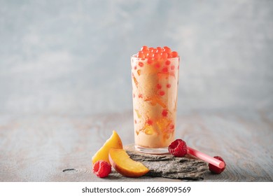 Cold iced peach raspberry bubble tea with juice balls in glass