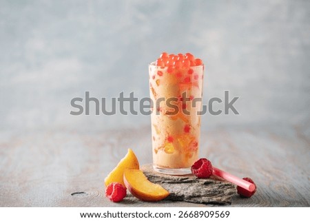 Cold iced peach raspberry bubble tea with juice balls in glass