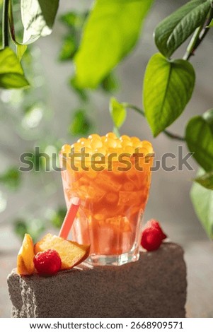 Cold iced peach raspberry bubble tea with juice balls in glass
