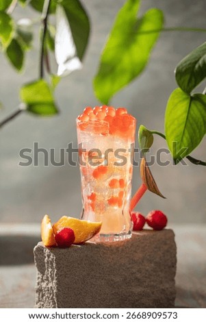 Cold iced peach raspberry bubble tea with juice balls in glass