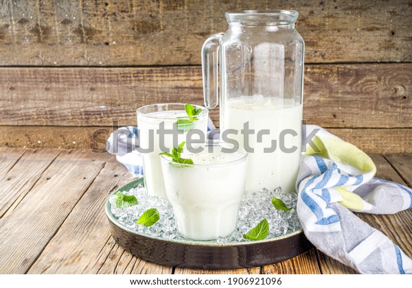 Cold Indian drink Lassi, iced\
coconut Lassi drink with mint leaf, wooden background copy\
space