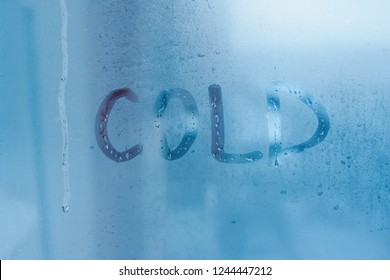 COLD - inscription on glass close-up with condensation. Background with water drops on the window with high humidity indoors