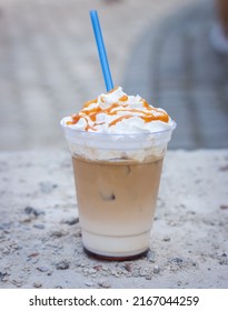 Cold Latte With Whipped Cream And Drinking Straw. Iced Latte Decorated With Salt Caramel Topping. Cold Drinks. Frappe Coffee With Straw. Frozen Cappuccino With Syrup. Coffee To Go. Summer Drinks.