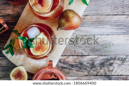Cold lemonade cocktail with figs on rustic wooden background. Top view with copy space