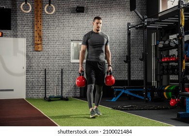 Cold Look And Focus On Training. Adult Muscular Man In Sportswear Carries Around Weights In His Hands And Walks Lightly Through The Gym. Good Figure And Body Position, Complete Commitment To Training