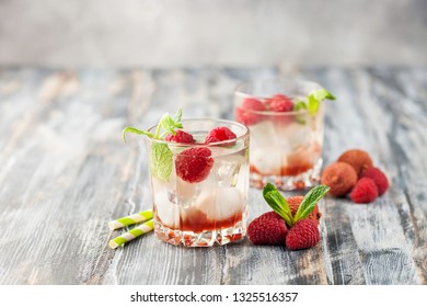 Cold Lychee And Raspberry Cocktail. The Summer Tropical Refreshing Litchi Drink On A Gray Wooden Background