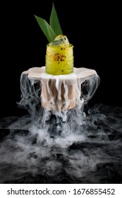 Cold mango lemonade surrounded by smoke on a dark background