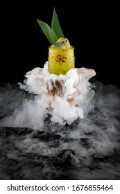 Cold mango lemonade surrounded by smoke on a dark background