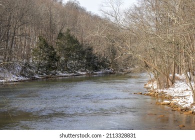 Cold Morning At The Loyalhanna Creek Located In Western Pennsylvania. Snow On The Riverbank, Flowing Water, Trees, Ice And Wildlife.