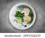 Cold Okroshka Soup with Eggs, Vegetables, Meat, Herbs and Kefir. Top view, on a gray background.