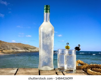 Cold Ouzo Bottle With Glasses On Sea Background