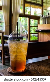 Cold peach tea in plastic cup on wooden table in coffee shop.