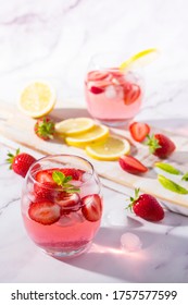 Cold Pink Strawberry Flavoured Gin And Tonic Garnished With Fresh Fruits, Lemon And Mint Leaves.