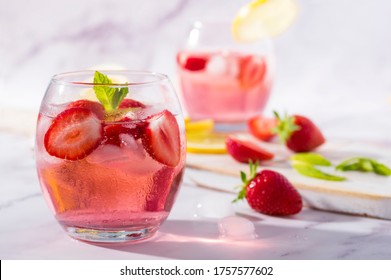 Cold Pink Strawberry Flavoured Gin And Tonic Garnished With Fresh Fruits, Lemon And Mint Leaves.