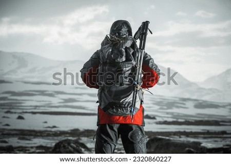 Cold and Rainy Weather on a Hike. Men with Backpack and Trekking Poles Facing Extreme Wilderness Conditions Ahead of Him. 