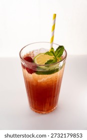 Cold raspberry lime cocktail with mint leaves, ice, and a yellow striped straw in a glass, ready for refreshment