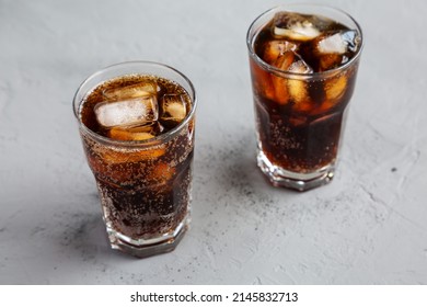 Cold Refreshing Dark Cola with Ice Cubes on a gray background, low angle view. 