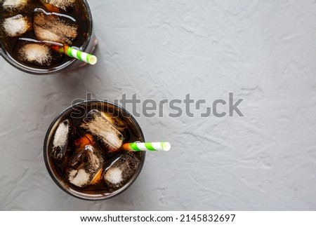 Cold Refreshing Dark Cola with Ice Cubes, Straws on a gray background, top view. Flat lay, overhead, from above.