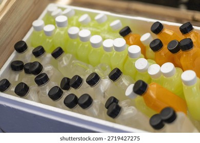 Cold refreshing plastic bottle drinks with yellow juice and orange beverage inside white foam box cooler ready for summer refreshment event or picnic