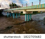 Cold river flowing under the rustic cement bridge. High and fast water rising in Bayou River with downtown Houston in background under cloud blue sky. Heavy rains from Harvey Tropical Hurricane storm