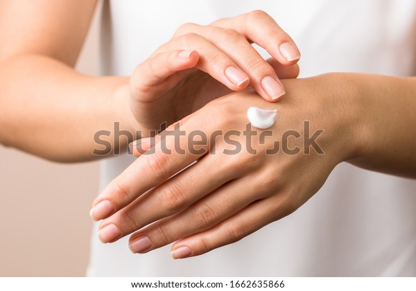 cold season hands skin protection.\
closeup woman applying protective cream on\
hands.