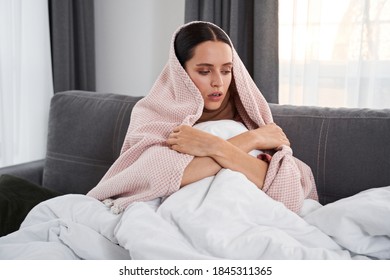 So Cold! Sick Caucasian Woman Freezes During A Cold. Young Pretty Brunette Having Chills And Warming Herself While Having Seasonal Virus Problem. Stock Photo