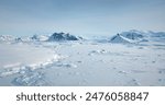 Cold South Pole winter landscape in sunny day. Snow covered frozen polar ocean, mountain range in background. Antarctica aerial majestic seascape drone view. Beauty of wild untouched nature. Travel