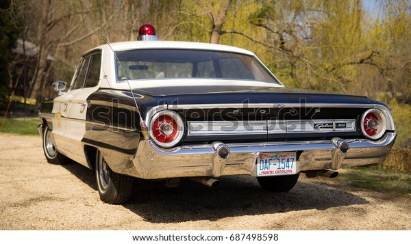 Cold Spring Harbor, USA - April 11\
2016: Vintage police car with a single red beacon light on the roof\
is parked on a street in Cold Spring Harbor,\
USA.